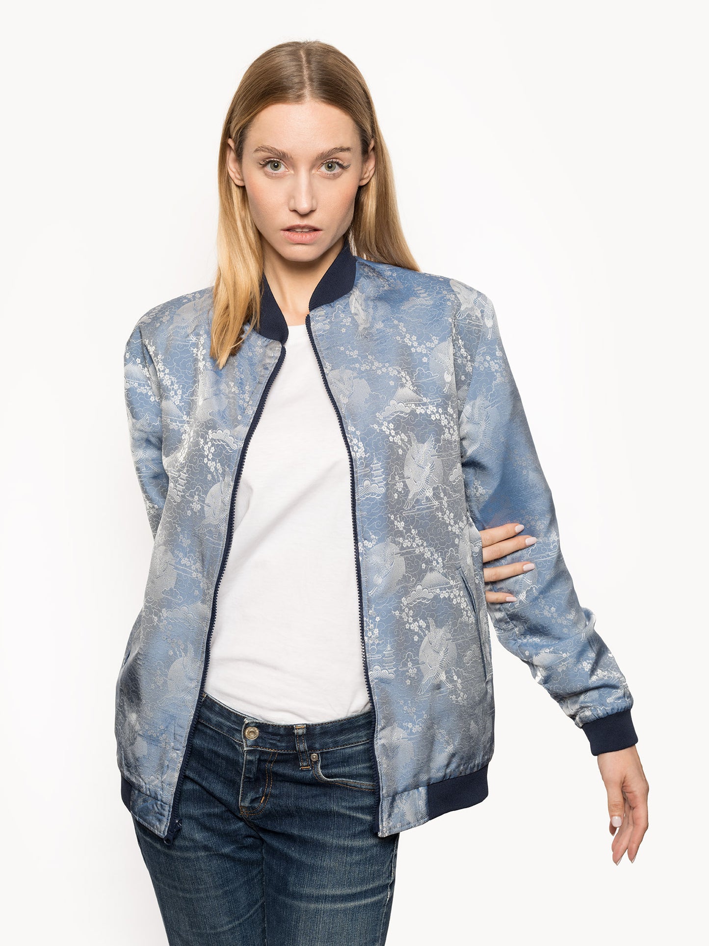 "Introducing Kaelu's exclusive 'DJINN' silk bomber jacket, numbered 1 to 20. Handcrafted in Vietnam with authentic Vietnamese silk, this reversible wonder showcases a stunning combination of silver and blue, adorned with graceful heron bird and mount fuji motifs. A true standout piece, offering a departure from the traditional, it's a symbol of sophistication and urban flair."