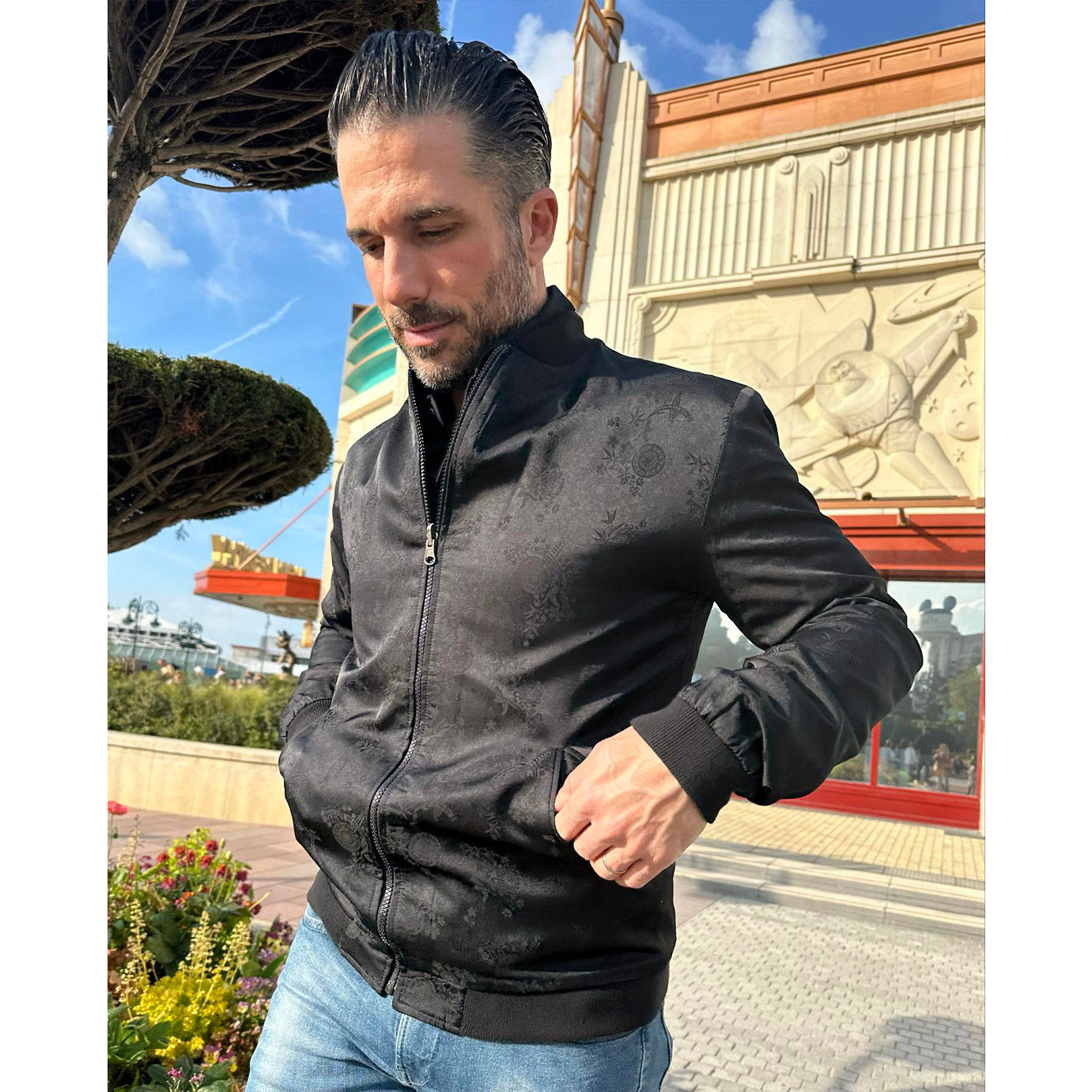 Geoffroy wearing the black side of his reversible Kaelu silk bomber jacket with blue jeans and a black shirt, channeling a vintage 1950s vibe.