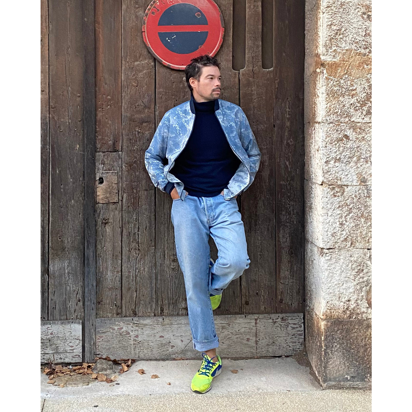 Raphaël Hiribarne, founder of Kaelu, wearing a silk bomber jacket with a turtleneck and eye-catching sneakers — a look that blends elegance and urban style.