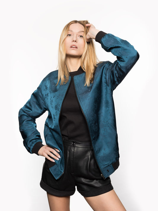 "Introducing Kaelu's exclusive 'DJINN' silk bomber jacket, numbered 1 to 20. Meticulously crafted in Vietnam using authentic Vietnamese silk, this reversible marvel features a refined blend of green and black, exuding subtle classiness. Unlike the bold Japanese sukajan, this piece offers understated luxury with a nod to urban sophistication."