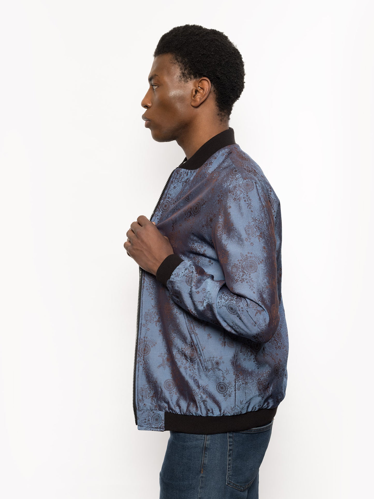 "Kaelu's limited edition 'DJINN' silk bomber jacket, numbered 1 to 20. Handcrafted in Vietnam with authentic Vietnamese silk, this reversible jacket offers versatility with one side in dark gray and the other in blue gray. Combining Asian luxury with urban style, it's fairtrade and fashion-forward, epitomizing streetwear sophistication."
