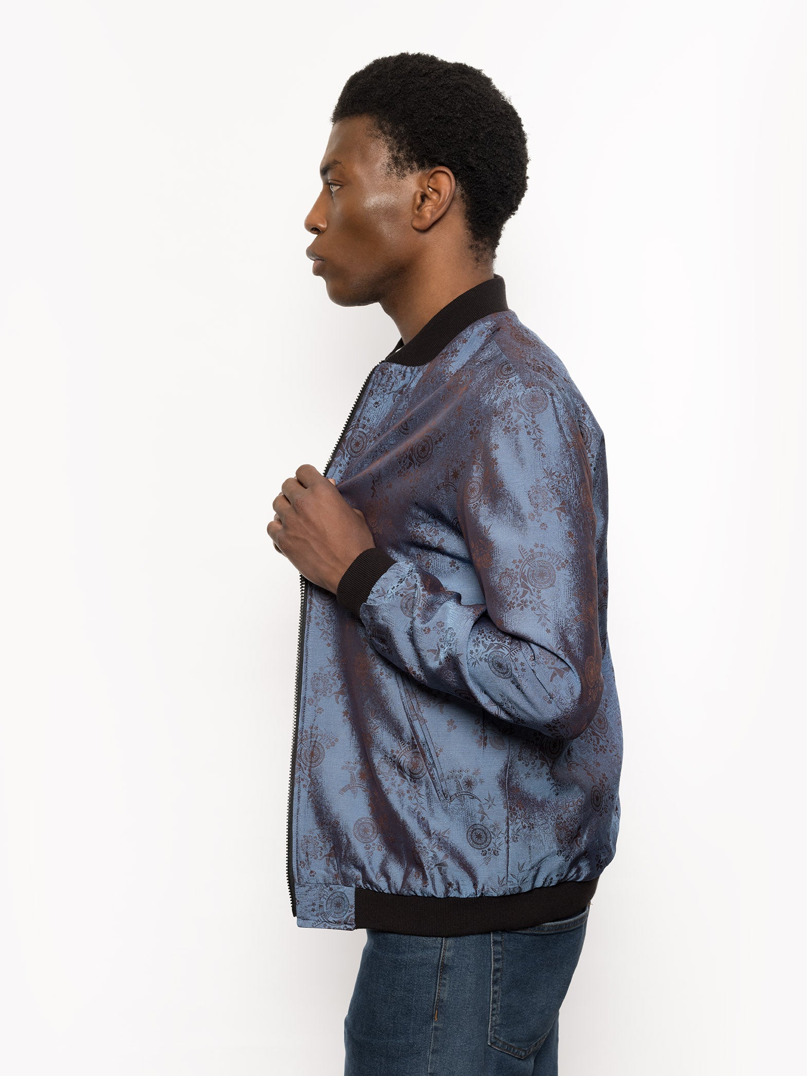 "Kaelu's limited edition 'DJINN' silk bomber jacket, numbered 1 to 20. Handcrafted in Vietnam with authentic Vietnamese silk, this reversible jacket offers versatility with one side in dark gray and the other in blue gray. Combining Asian luxury with urban style, it's fairtrade and fashion-forward, epitomizing streetwear sophistication."