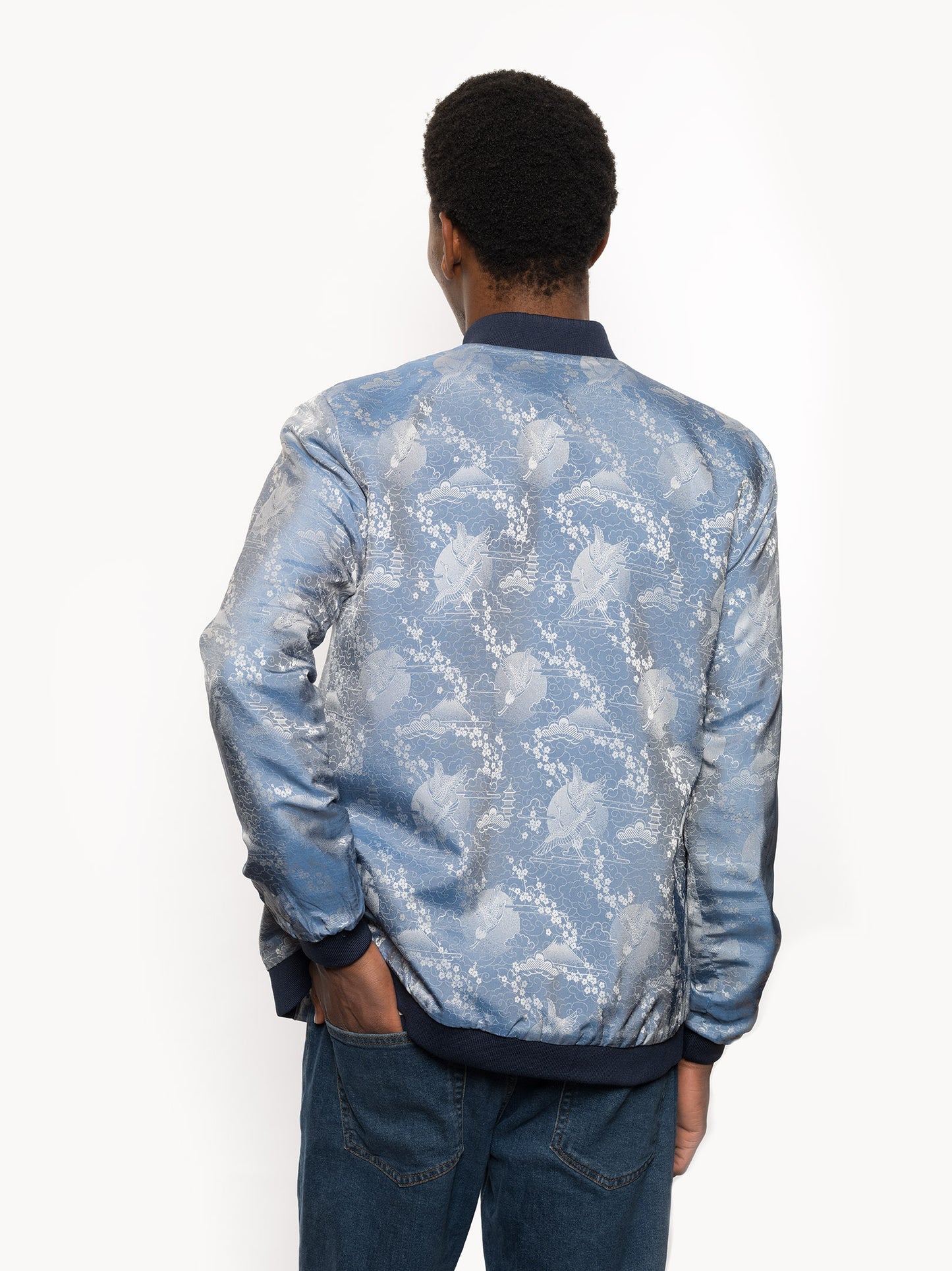 "Introducing Kaelu's exclusive 'DJINN' silk bomber jacket, numbered 1 to 20. Handcrafted in Vietnam with authentic Vietnamese silk, this reversible wonder showcases a stunning combination of silver and blue, adorned with graceful heron bird and mount fuji motifs. A true standout piece, offering a departure from the traditional, it's a symbol of sophistication and urban flair."