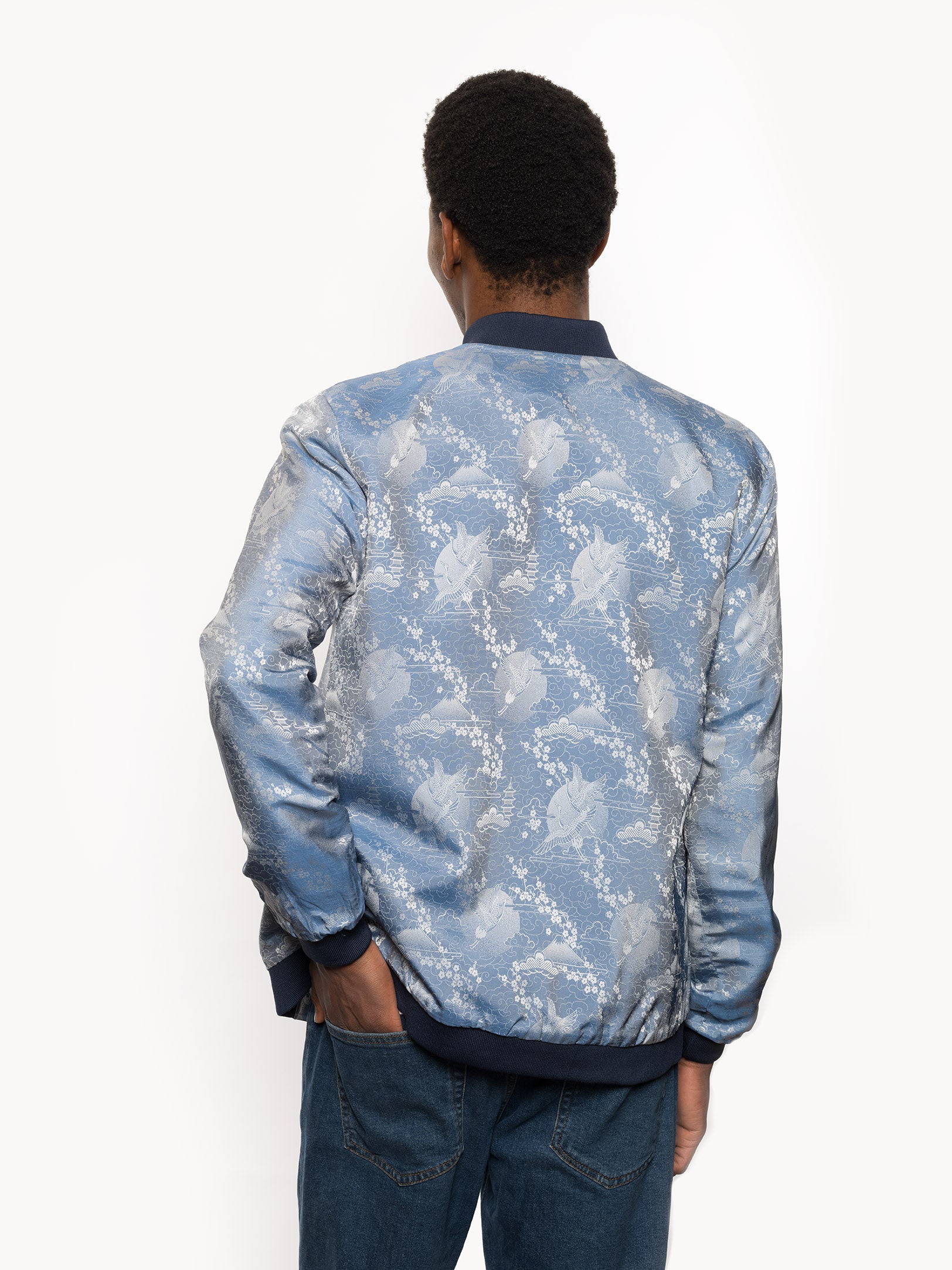 "Introducing Kaelu's exclusive 'DJINN' silk bomber jacket, numbered 1 to 20. Handcrafted in Vietnam with authentic Vietnamese silk, this reversible wonder showcases a stunning combination of silver and blue, adorned with graceful heron bird and mount fuji motifs. A true standout piece, offering a departure from the traditional, it's a symbol of sophistication and urban flair."