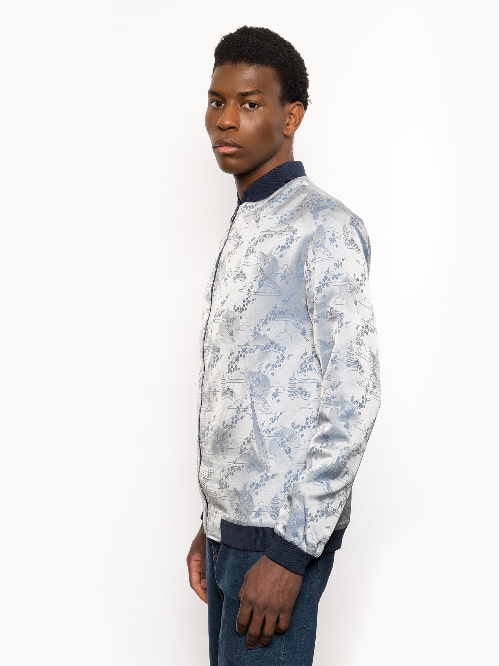 "Introducing Kaelu's exclusive 'DJINN' silk bomber jacket, numbered 1 to 20. Handcrafted in Vietnam with authentic Vietnamese silk, this reversible wonder showcases a stunning combination of silver and blue, adorned with graceful heron bird and mount fuji motifs. A true standout piece, offering a departure from the traditional, it's a symbol of sophistication and urban flair."