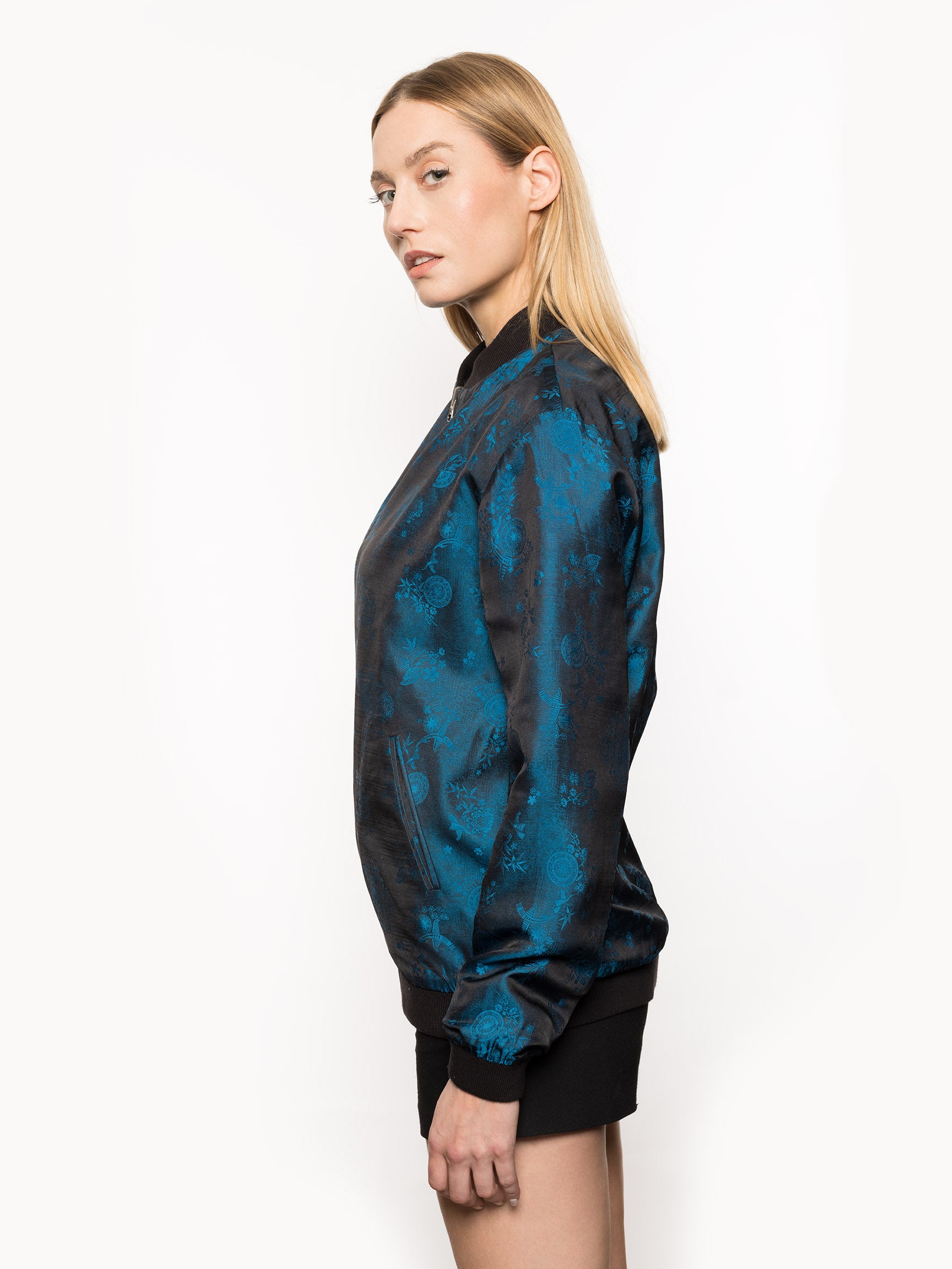 Kaelu's limited edition 'DJINN' silk bomber jacket, numbered 1 to 20. Handcrafted in Vietnam with authentic Vietnamese silk, this reversible jacket offers versatility with one side in striking blue and the other in sleek black. Combining Asian luxury with urban style, it's fairtrade and fashion-forward, epitomizing streetwear sophistication. Side shot