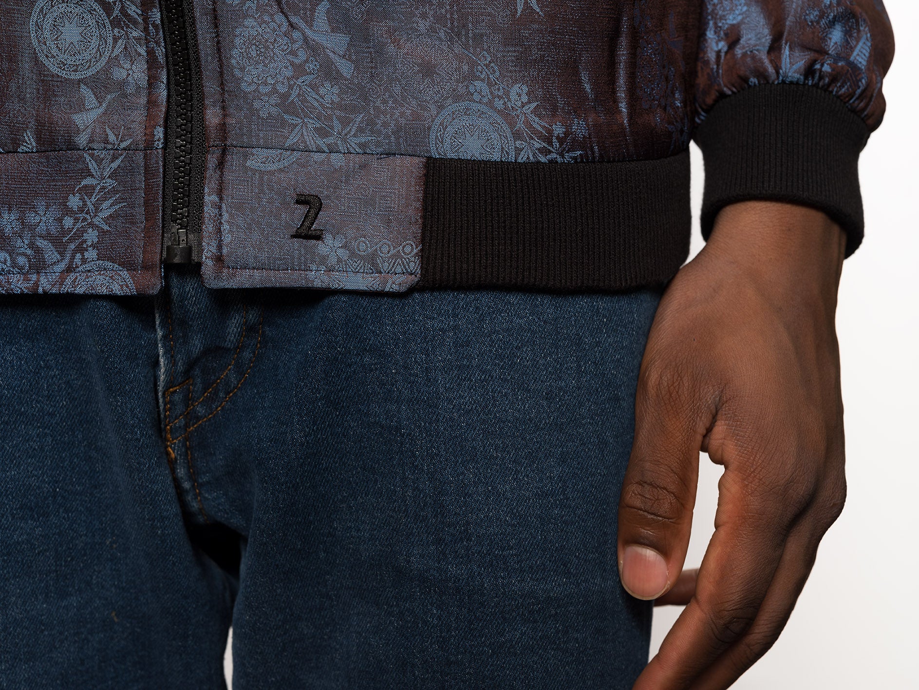"Kaelu's limited edition 'DJINN' silk bomber jacket, numbered 1 to 20. Handcrafted in Vietnam with authentic Vietnamese silk, this reversible jacket offers versatility with one side in dark gray and the other in blue gray. Combining Asian luxury with urban style, it's fairtrade and fashion-forward, epitomizing streetwear sophistication."