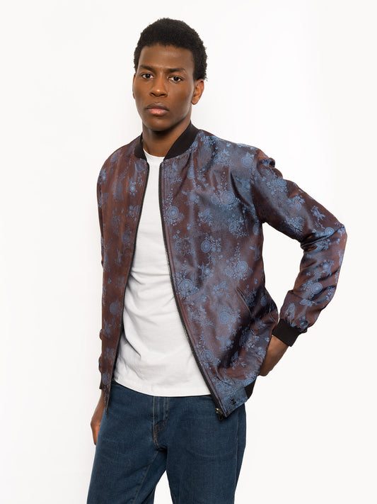 "Kaelu's limited edition 'DJINN' silk bomber jacket, numbered 1 to 20. Handcrafted in Vietnam with authentic Vietnamese silk, this reversible jacket offers versatility with one side in dark gray and the other in blue gray. Combining Asian luxury with urban style, it's fairtrade and fashion-forward, epitomizing streetwear sophistication."