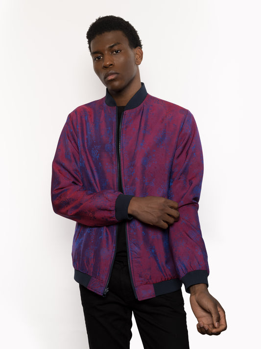 "Presenting Kaelu's exclusive 'DJINN' silk bomber jacket, numbered 1 to 20. Handcrafted in Vietnam from authentic Vietnamese silk, this reversible masterpiece offers two distinct hues of purple: one leaning towards a deep blue-purple, the other towards a soft pink-purple, complementing black skin tones impeccably. Embrace understated elegance with this piece, a departure from the vibrant Japanese sukajan, exuding sophistication in every detail."